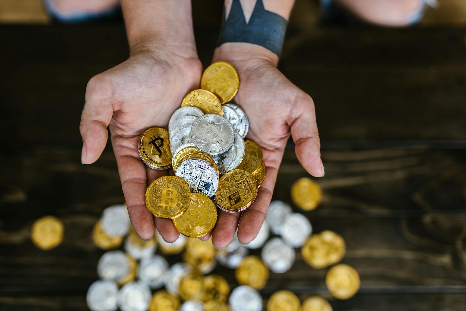 high angle shot of person holding gold and silver bitcoins